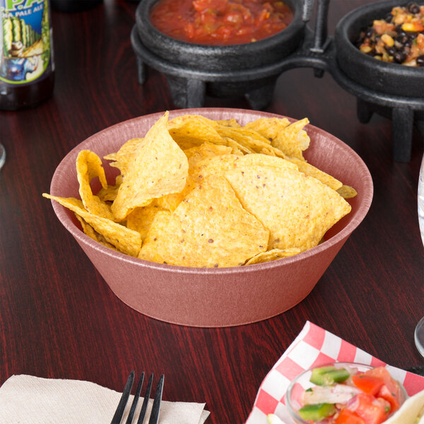 A paprika polyethylene round basket filled with chips on a table.
