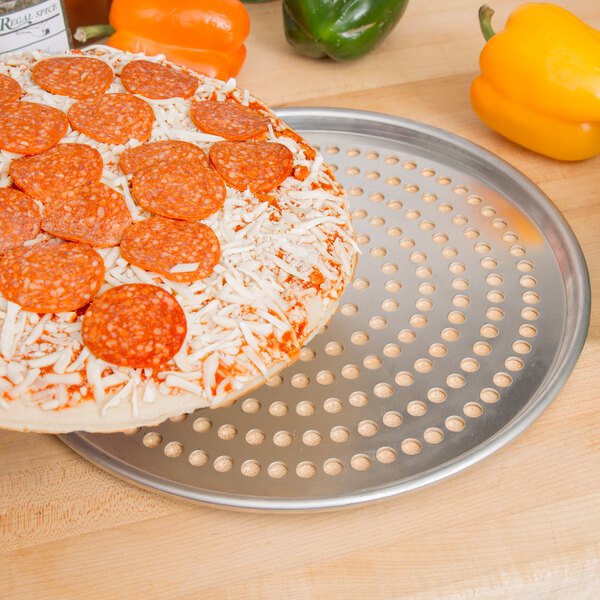 An American Metalcraft Super Perforated Heavy Weight Aluminum pizza pan holding a pizza with pepperoni and cheese.