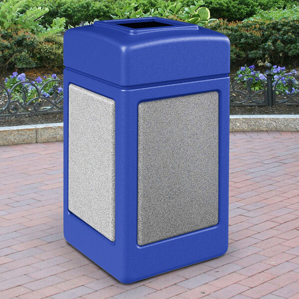 A blue Commercial Zone StoneTec waste receptacle with Ashtone panels on a brick surface.