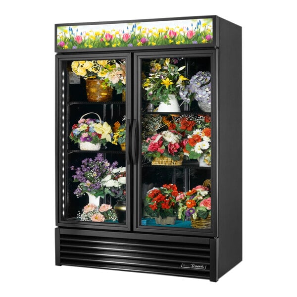 A True black refrigerated glass display case filled with flowers.
