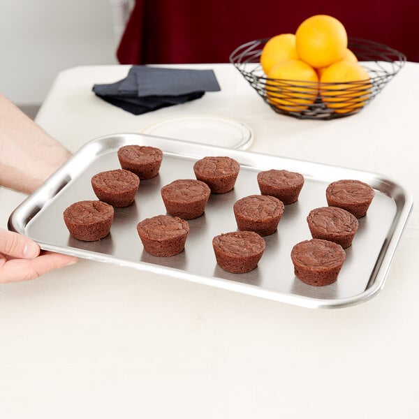 A Vollrath stainless steel serving tray holding brown cupcakes.
