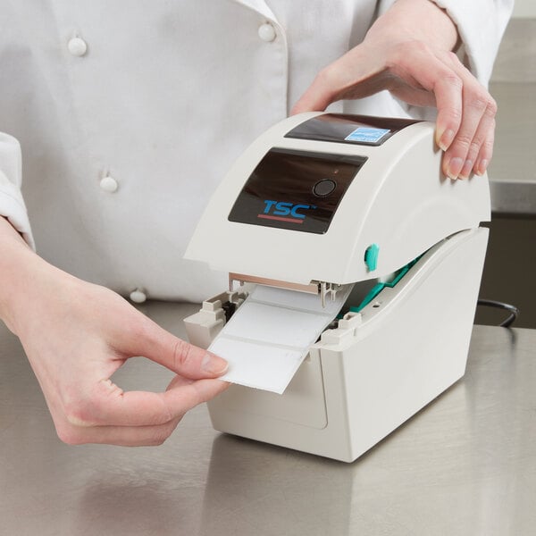 A person using a Cardinal Detecto thermal label printer to print a label.