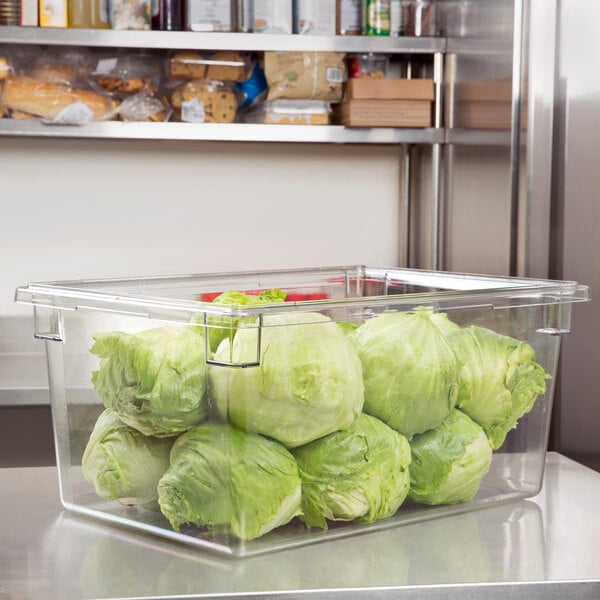 A clear plastic Cambro food storage container filled with lettuce on a kitchen counter.