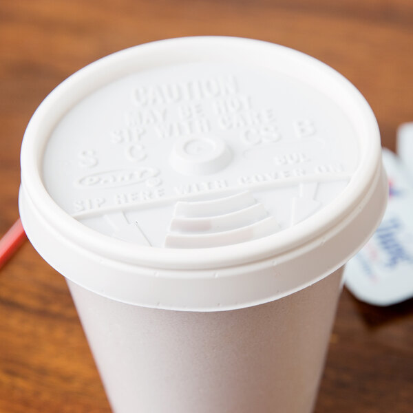A white plastic Dart lid on a white foam cup.