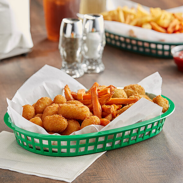 A green Tablecraft oval platter basket filled with fried food on a table.