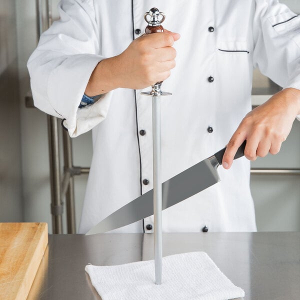 A chef using a Victorinox knife sharpening steel with a rosewood handle to sharpen a knife.