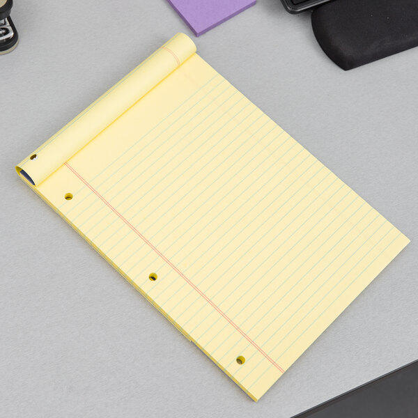 An Ampad yellow lined writing pad on a grey surface.
