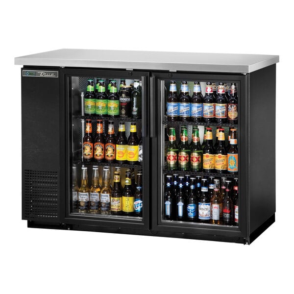 A black True back bar refrigerator with beer bottles inside.