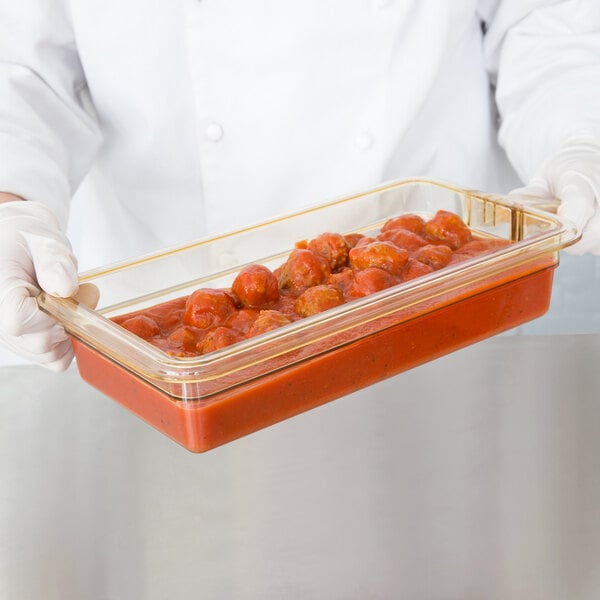 A person holding a Cambro H-Pan with food in it.