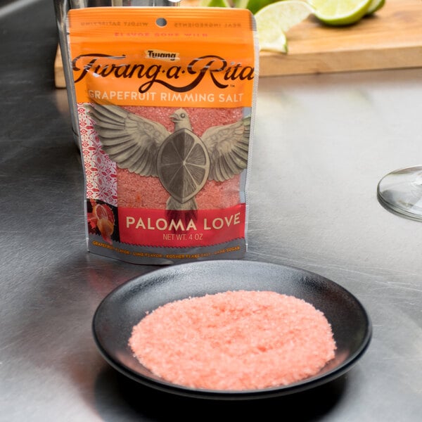 A bag of Twang-a-Rita Paloma Love grapefruit salt next to a bowl of pink salt.