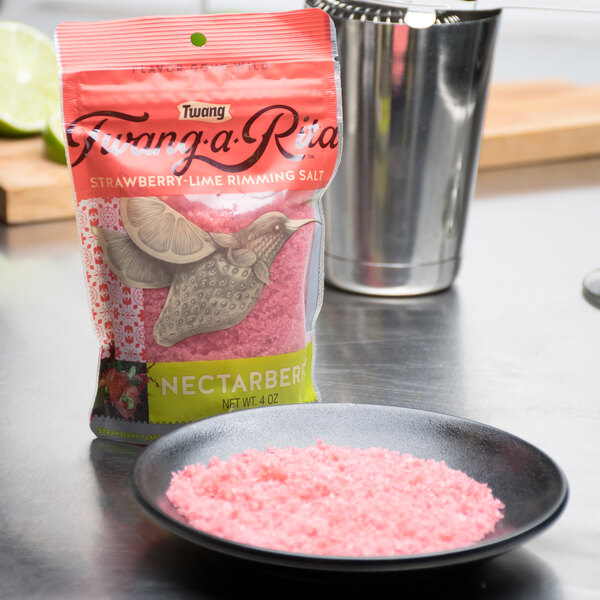 A bag of Twang-a-Rita Nectarberry strawberry pink salt next to a bowl of pink salt.