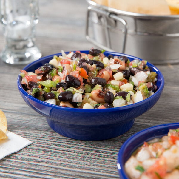 A Thunder Group cobalt blue salsa dish filled with black bean and corn salsa on a table.