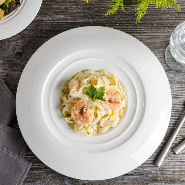 A white porcelain round pasta bowl filled with pasta and shrimp.
