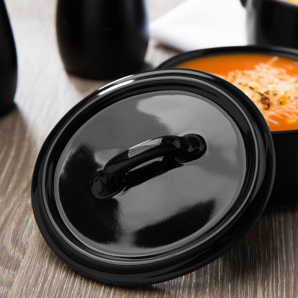 A black Bon Chef oval cocotte lid on a bowl of soup.