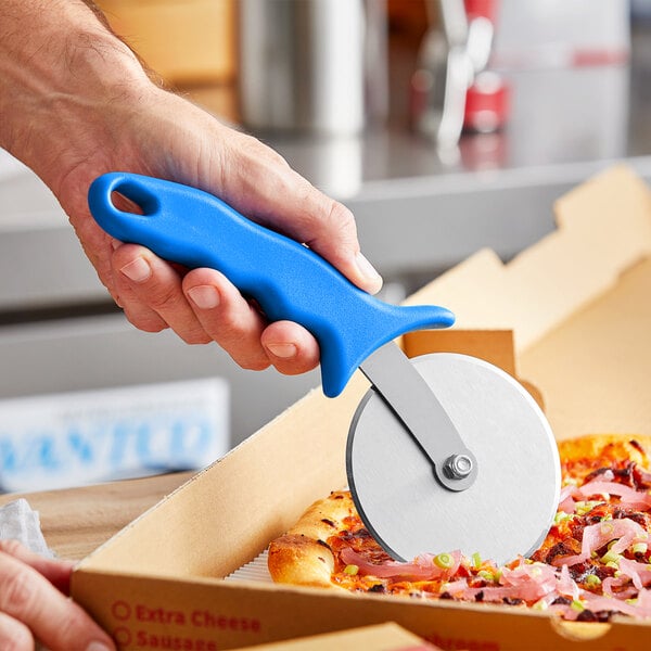 A person using a GI Metal pizza cutter with a blue plastic handle to cut a pizza.