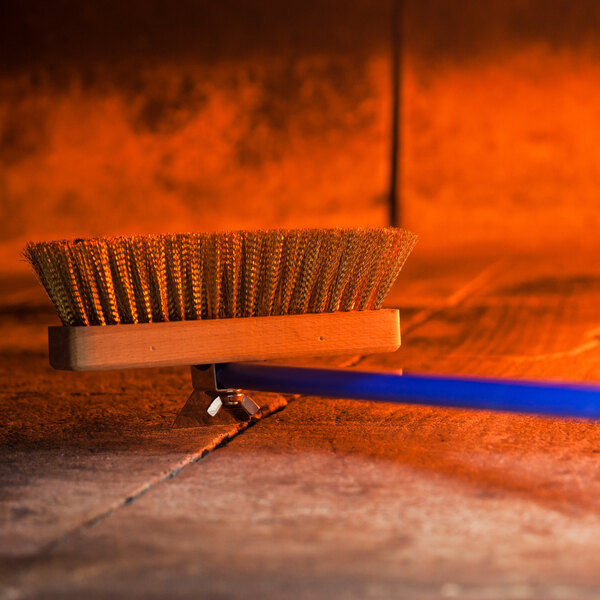 A GI Metal brass bristle pizza oven brush on a wood surface.