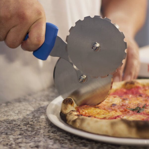 A hand using a GI Metal stainless steel double wheel pizza cutter to cut a pizza.