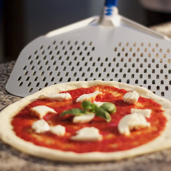 An Azzurra anodized aluminum square perforated pizza peel with a pizza with cheese and basil on it.