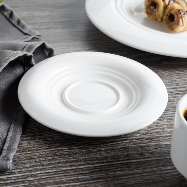A white Bon Chef porcelain demi saucer on a white surface with food on it.