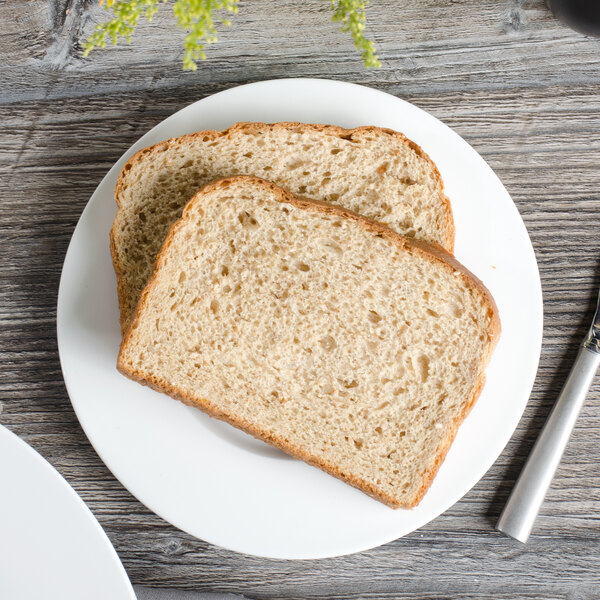 A white Bon Chef bone china bread and butter plate with two slices of bread and a fork.