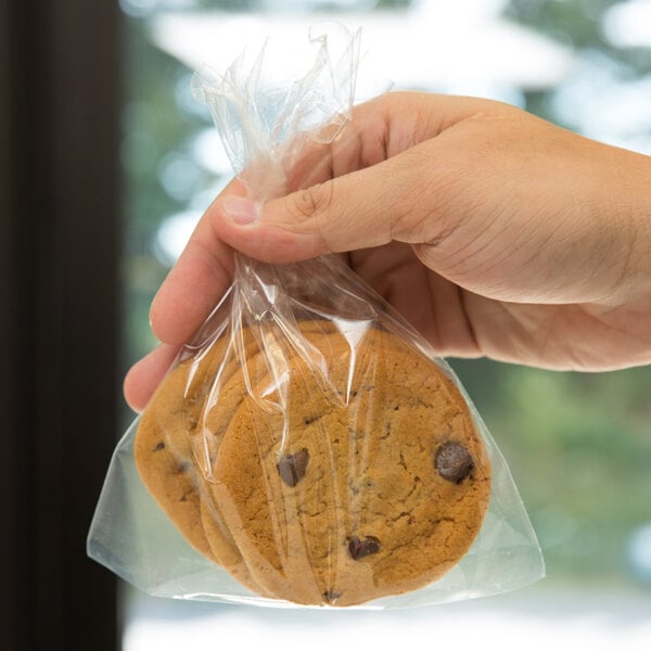A hand holding a plastic LK Packaging food bag of cookies.