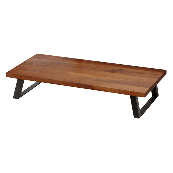 A GET walnut wood riser with black metal legs on a wooden table.