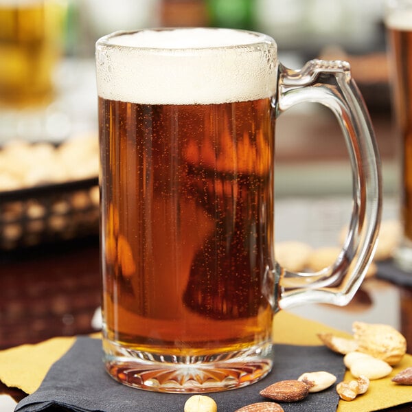 A Libbey glass mug of beer on a napkin with foamy beer.