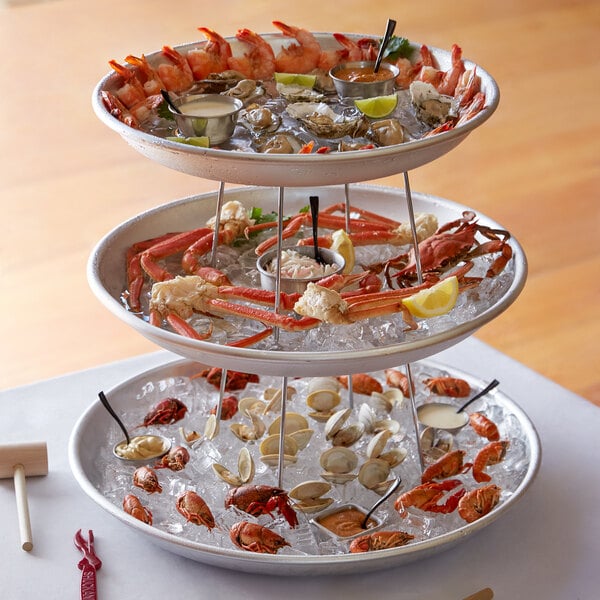 A three tiered Choice Seafood Tower with seafood, crab legs, and sauces on ice.