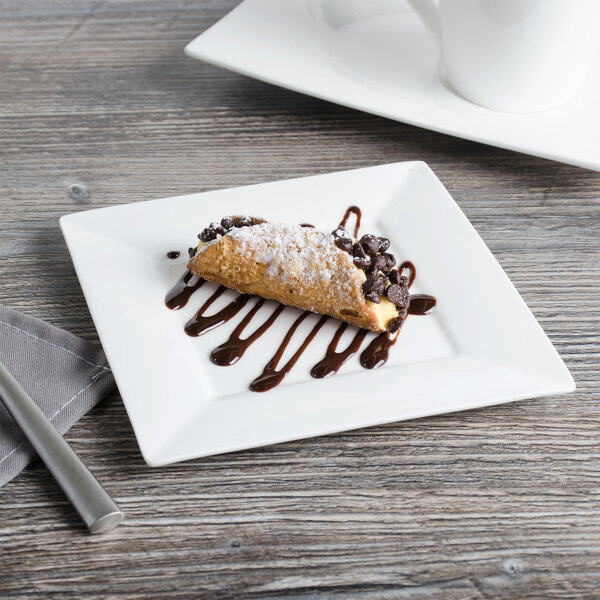 A white Bon Chef bone china square plate with a chocolate covered pastry and a fork.
