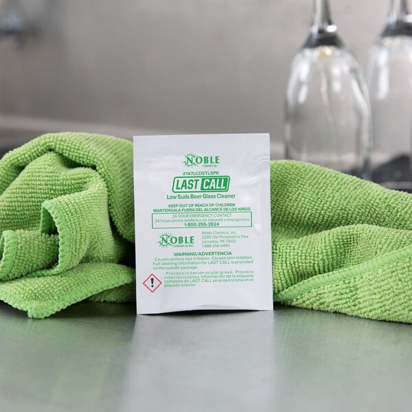A white package of Noble Chemical Last Call powdered glass cleaner packets with green and white labeling.