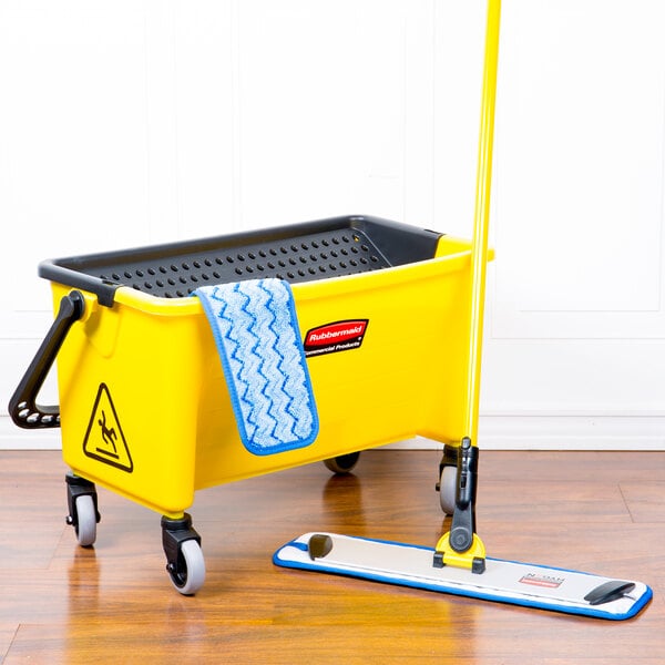 A Rubbermaid yellow mop pad on a Rubbermaid blue mop in a bucket on a wood floor.