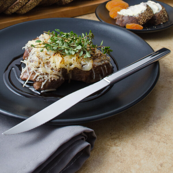 A plate with food and a Walco stainless steel steak knife.