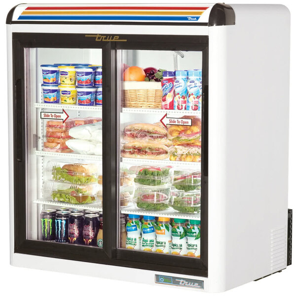 A white True countertop refrigerator with food and drinks inside.
