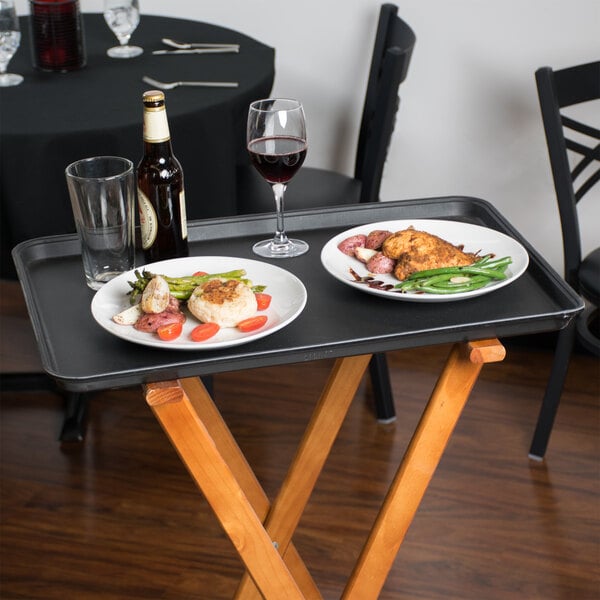 A Cambro non-skid serving tray with plates and a glass of wine on it.