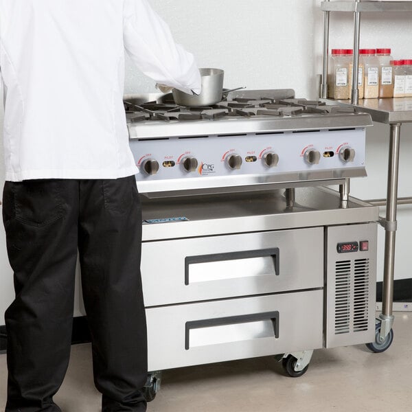 A person standing in front of a Cooking Performance Group 6 burner countertop range.
