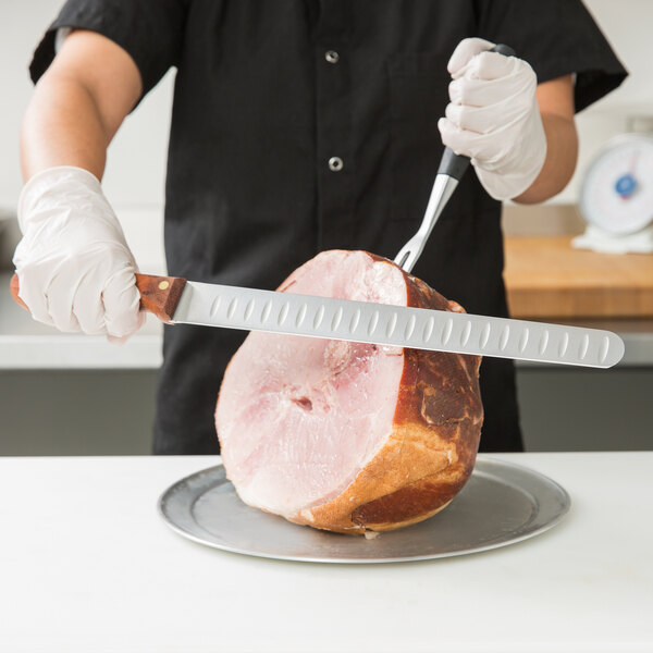 A person using a Mercer Culinary Praxis slicer knife to cut ham.