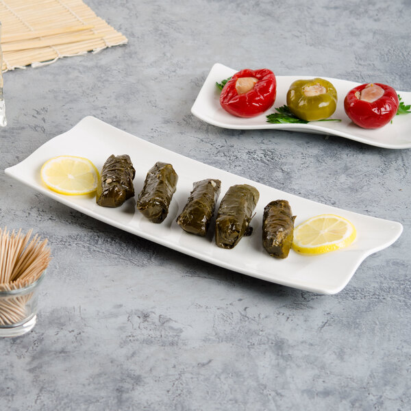 A Villeroy & Boch white porcelain rectangular plate with stuffed grape leaves and a lemon slice.