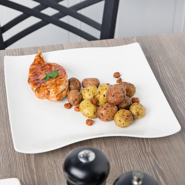 A Villeroy & Boch white porcelain square plate with chicken and potatoes on it.