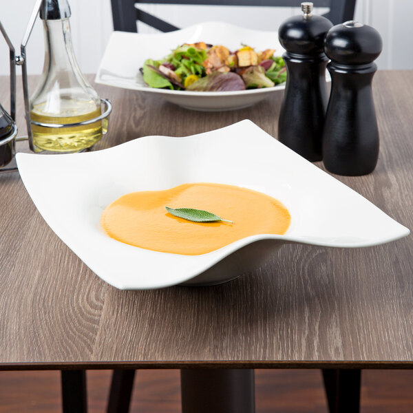 A Villeroy & Boch white porcelain deep bowl filled with soup on a table.