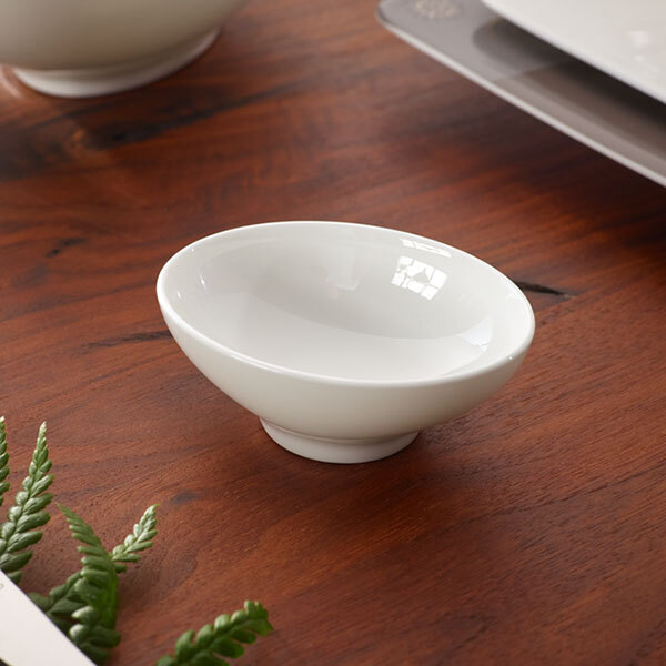 A Villeroy & Boch white bone porcelain dip bowl on a wood table.