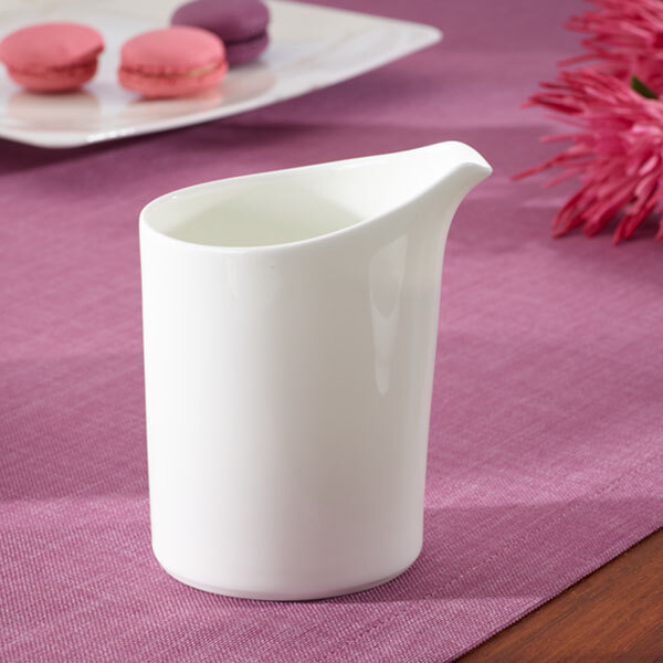 A white Villeroy & Boch porcelain creamer on a purple tablecloth.