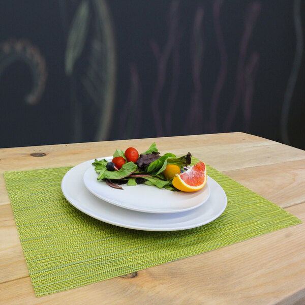 A plate of salad and fruit on a lime green woven vinyl rectangle placemat.