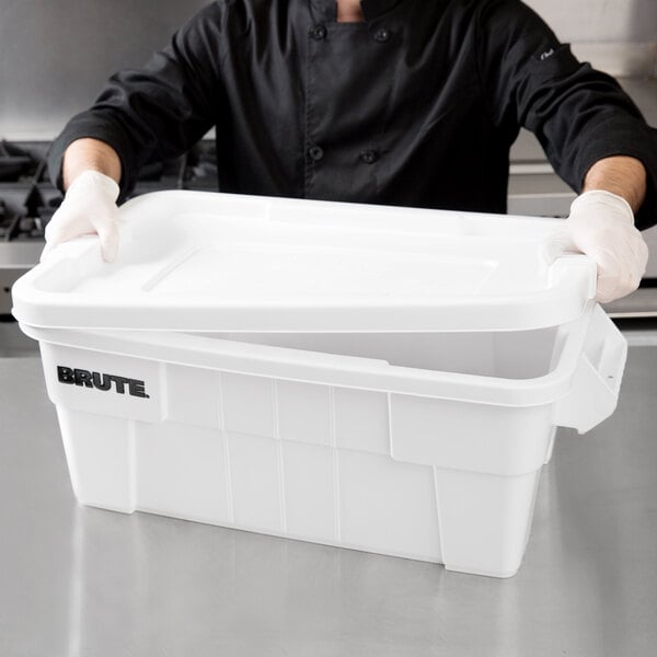 A man in a chef's uniform holding a white Rubbermaid tote with a lid.