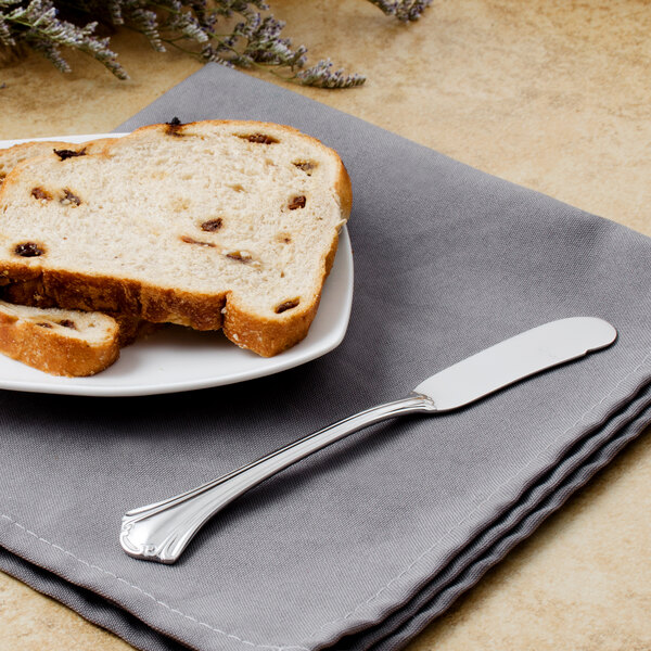 A plate of bread with a Walco stainless steel butter spreader on it.