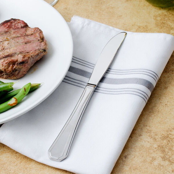 A Walco stainless steel dinner knife on a plate of steak and green beans.