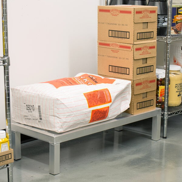 A Regency aluminum dunnage rack holding a white bag of food.