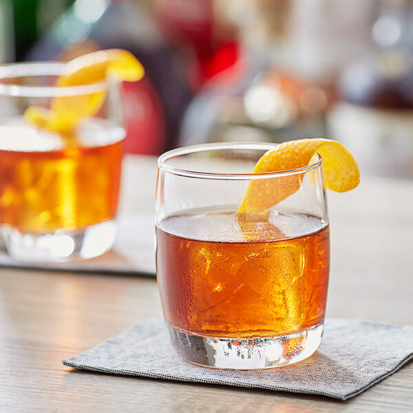 Two Acopa old fashioned glasses with whiskey and orange slices.