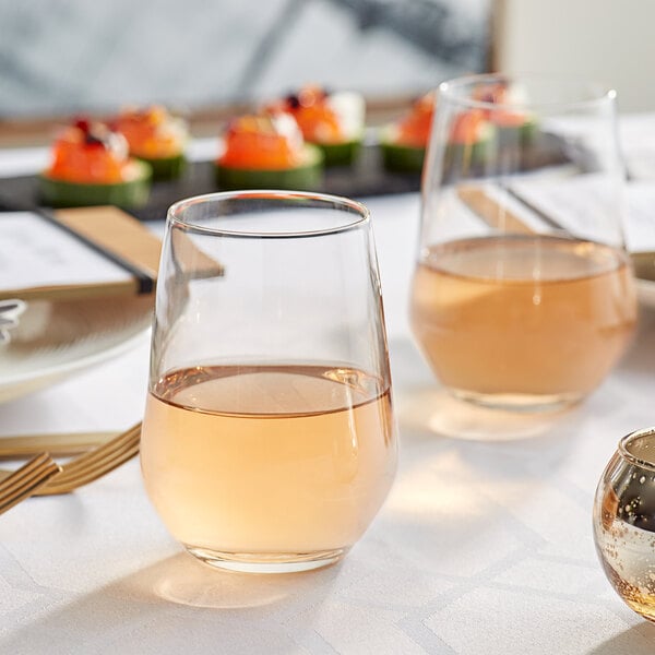 A table with Acopa tall stemless wine glasses filled with wine on it.