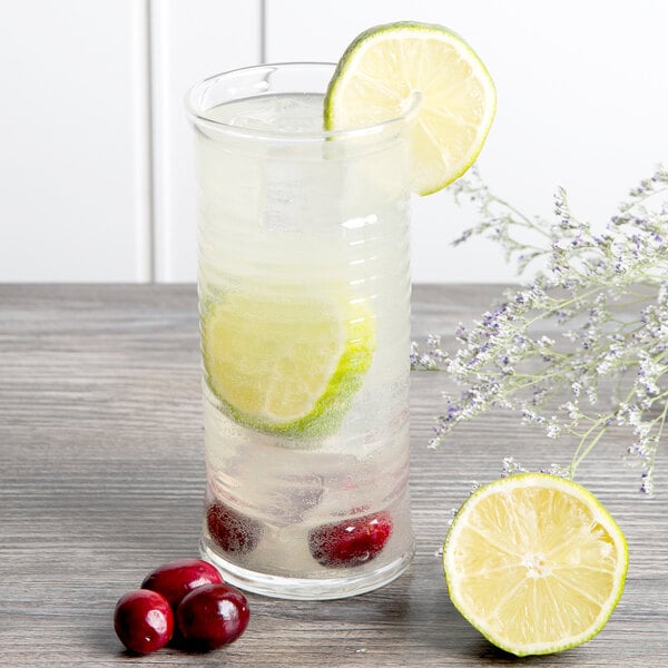 An Arcoroc highball glass with ice water and a lime wedge.
