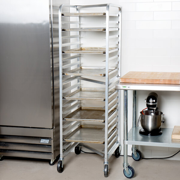 A Channel metal sheet pan rack with trays next to a refrigerator.